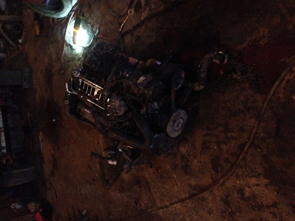 Engine block with belts and pulleys, partially obscured by dirt and wiring