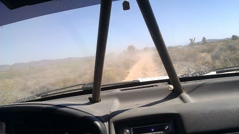 1996 Ford Bronco - Driving through a dusty desert landscape, view from inside the vehicle.