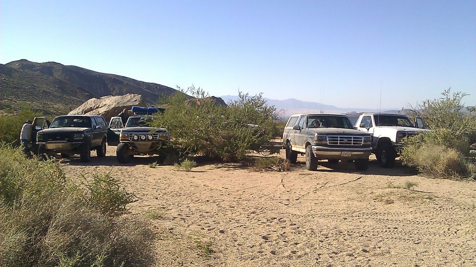 1996 Ford Bronco and other SUVs parked in desert with mountains in background