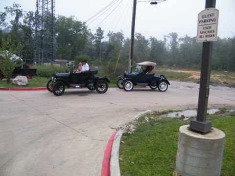 1909 Ford Model T - Two vintage Ford Model T touring cars are seen on a road, one with a tan top and the other with a black top.