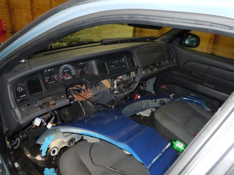 2001 Ford Crown Victoria - The interior of a car shows disassembled dashboard components and exposed wiring, indicating repair or modification.