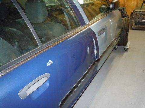 2001 Ford Crown Victoria - This 2001 Ford Crown Victoria shows significant body damage on its side, with mismatched paint colors indicating repairs.