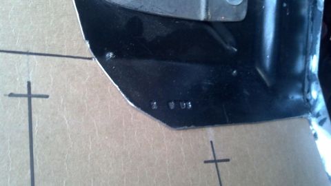 1964 Ford Fairlane - A black metal component with stamped identification numbers is shown against a marked cardboard background.