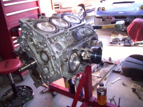 1995 Ford Probe - Engine block on a red stand, with tools and another vehicle in the background.