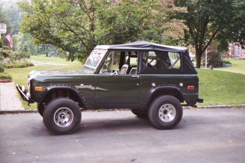 1976 Ford Bronco - This 1976 Ford Bronco is shown from the side, a dark green exterior and a black soft top.