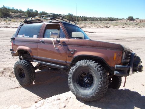 1986 Ford Bronco II - This modified 1986 Ford Bronco II is shown in a desert landscape, large off-road tires and a roof rack.