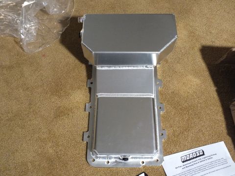 2003 Ford Crown Victoria - Fabricated aluminum oil pan shown from above with welded baffle, mounting flange, and a printed instruction sheet on carpet.