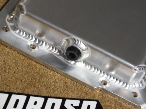 2003 Ford Crown Victoria - Macro shot of a TIG-welded threaded drain fitting and bolt holes on a fabricated aluminum oil pan, with a Moroso decal below.