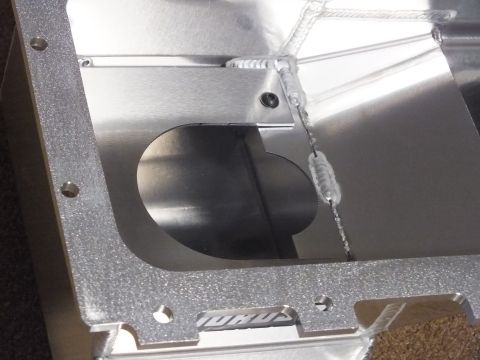 2003 Ford Crown Victoria - Macro view inside a fabricated aluminum oil pan showing a cutout opening, welded baffle, and cast-finish surfaces.