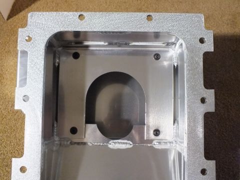 2003 Ford Crown Victoria - Macro view into a cast aluminum oil pan revealing the bolt flange and a welded U-shaped crank clearance opening.