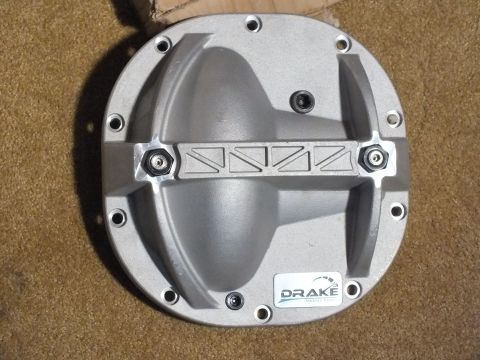 2003 Ford Crown Victoria - Cast aluminum Drake differential cover showing ribbed reinforcement, hex adjuster bolts, and bolt holes around the perimeter.