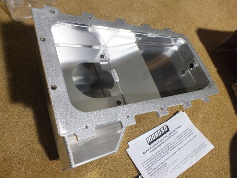 2003 Ford Crown Victoria - Top view into a fabricated aluminum Moroso oil pan showing internal baffling, a round pickup cutout, and a nearby instruction sheet.