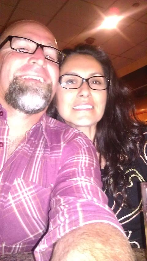 1996 Ford Bronco - A man and woman wearing glasses smile for a selfie in an indoor setting.