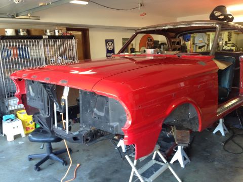1964 Ford Fairlane - The front end of a red 1964 Ford Fairlane is disassembled in a garage, supported by jack stands.