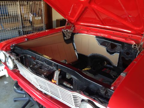 1964 Ford Fairlane - The engine bay of a red 1964 Ford Fairlane shows custom cardboard sound deadening panels being fitted.