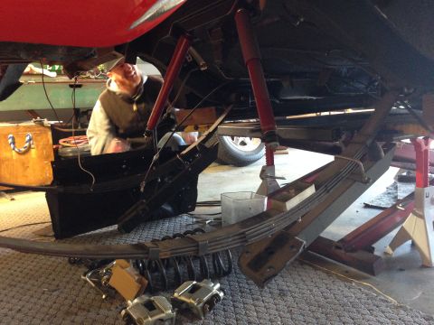 1964 Ford Fairlane - A person works on the underside of a vehicle, with suspension components laid out.