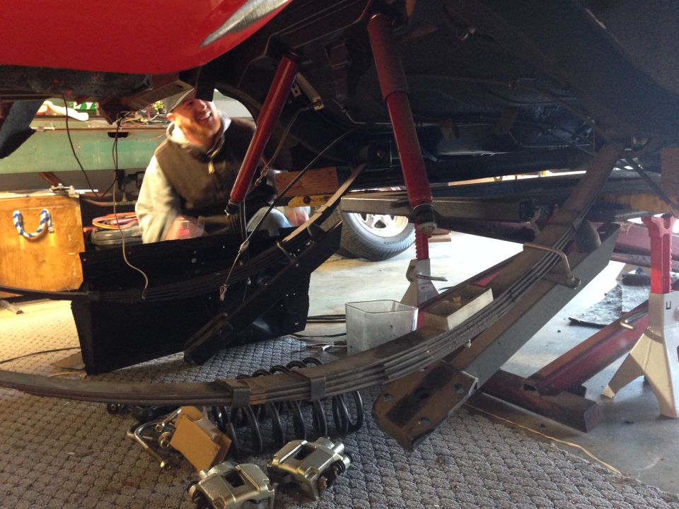 guy working on car suspension, leaf springs and shocks visible