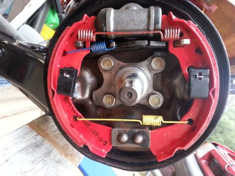 1991 Ford Festiva - Brake drum assembly showing red brake shoes, springs, and wheel cylinder.