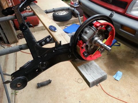 1991 Ford Festiva - A disassembled vehicle rear axle assembly is shown, with a Ford logo visible on a wooden support.