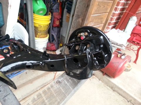 1991 Ford Festiva - A black painted rear axle assembly with brake drum is shown, possibly undergoing restoration or repair.