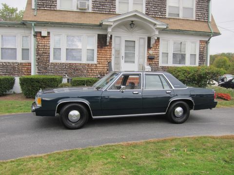 2001 Ford Crown Victoria - Side view of a dark green sedan parked on a driveway. The house behind it has cedar shingle siding.