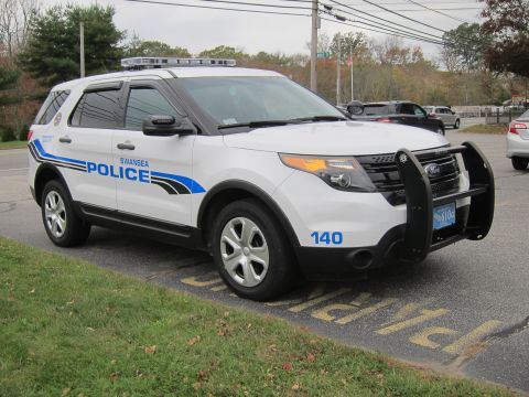 2001 Ford Crown Victoria - A white police SUV with 'SWANSEA POLICE' markings is parked on the side of the road.