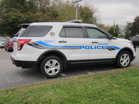 2001 Ford Crown Victoria - A white police SUV, likely a Ford Explorer, is parked on the side of the road with 'POLICE' and 'SWANSEA' markings.
