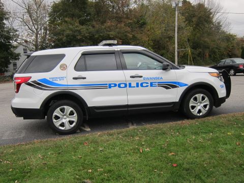 2001 Ford Crown Victoria - Police SUV parked on the side of the road with "EMERGENCY DIAL 911" visible.