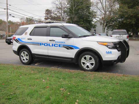 2001 Ford Crown Victoria - A white police SUV with "SWANSEA POLICE" markings is parked on a street, with another vehicle visible in the background.