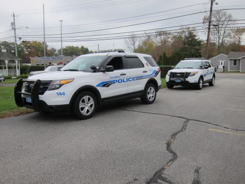 2001 Ford Crown Victoria - Two police SUVs are parked in a lot under an overcast sky.