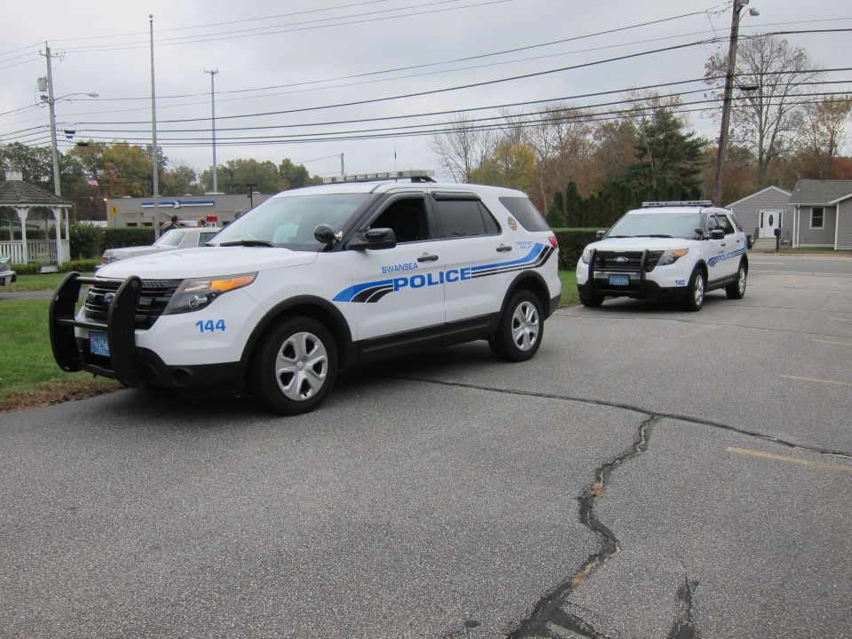 Two white police SUVs parked in a lot, one with 'SWANSEA POLICE' on the side