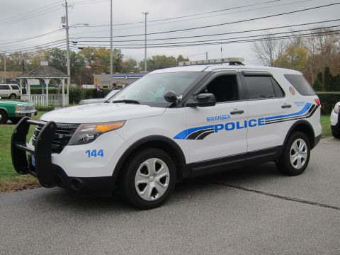 2001 Ford Crown Victoria - A police SUV is parked on a street with a gazebo and other vehicles in the background.