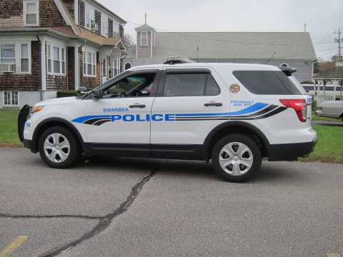 2001 Ford Crown Victoria - Side view of a white police SUV with 'SWANSEA POLICE' markings and emergency lights.