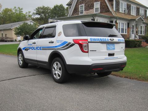 2001 Ford Crown Victoria - A white police SUV with 'SWANSEA POLICE' markings is seen from the rear on a street.