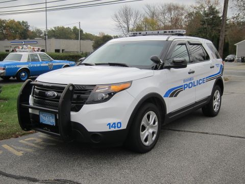 2001 Ford Crown Victoria - A white Ford police SUV is parked on asphalt, with another older police car visible in the background.