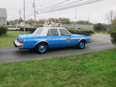 2001 Ford Crown Victoria - A vintage police car, marked 'HWY 3' and '2840', is parked on a paved surface next to a grassy area.