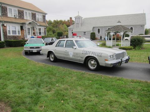 2001 Ford Crown Victoria - Two police cars are parked on a driveway in front of a building and a church.