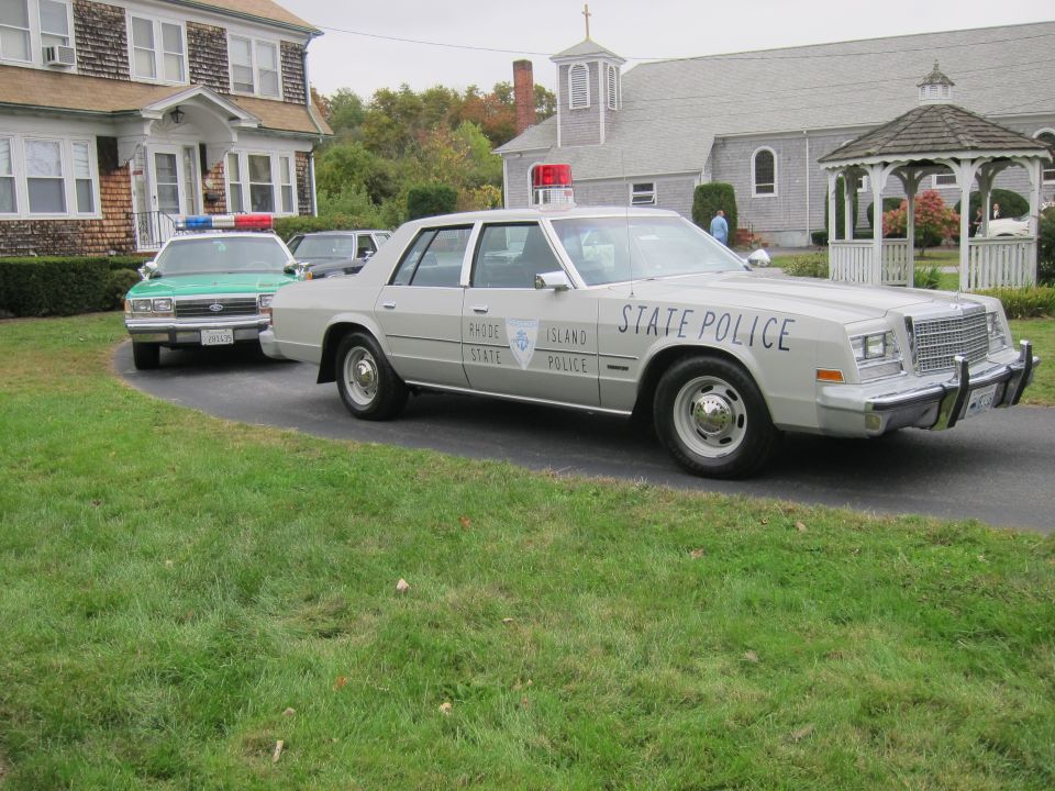 Gray Chrysler New Yorker police car with "STATE POLICE" text, red and blue lights