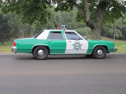 2001 Ford Crown Victoria - Side view of a vintage sheriff's car, likely from the 1980s, with a distinctive green and white paint scheme.
