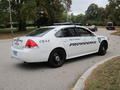 2001 Ford Crown Victoria - Providence police car parked on a street with trees and other vehicles in the background.