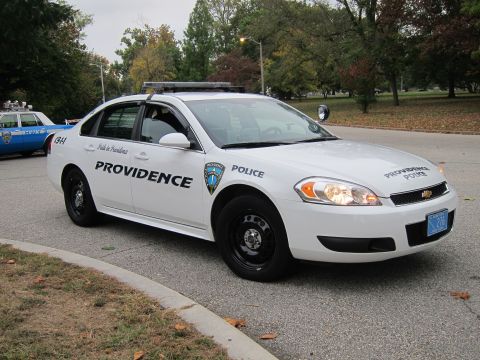2001 Ford Crown Victoria - A police car is parked on the street, with another police vehicle in the background.