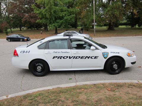 2001 Ford Crown Victoria - A white police car with 'Providence' text and a police emblem on the door is parked on a street.