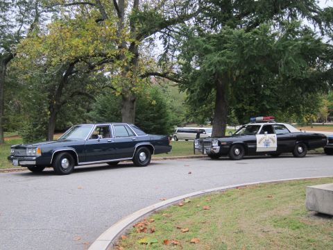 2001 Ford Crown Victoria - Photograph of two cars parked on a paved drive, including a CHP-liveried Ford sedan, not a technical document.