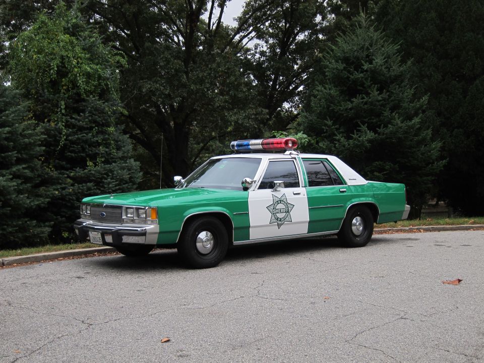 Green-and-white Sheriff Ford LTD Crown Victoria police car parked on pavement