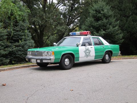 2001 Ford Crown Victoria - Photograph of a green-and-white sheriff Ford Crown Victoria police car, not a technical document.
