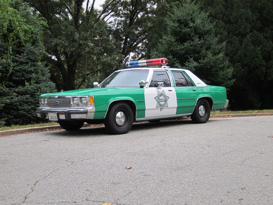 Green-and-white Sheriff Ford LTD Crown Victoria cruiser parked on a driveway