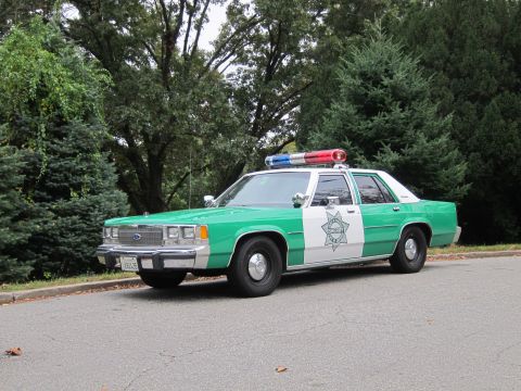 2001 Ford Crown Victoria - Photograph of a green-and-white sheriff Ford Crown Victoria police car, not a technical document.