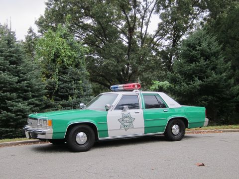 2001 Ford Crown Victoria - Photograph of a green and white Sheriff patrol sedan, not a technical document.