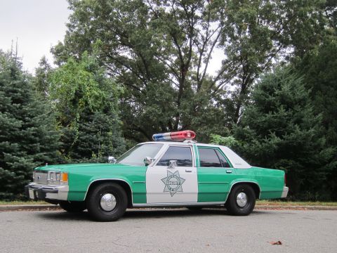2001 Ford Crown Victoria - Photograph of a green and white Sheriff patrol sedan, not a technical document.