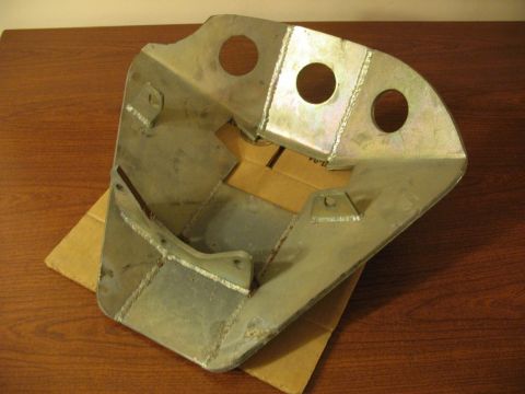 1994 Ford Bronco - A custom-fabricated metal bracket with three circular cutouts and several mounting tabs sits on a wooden surface, partially supported by a…